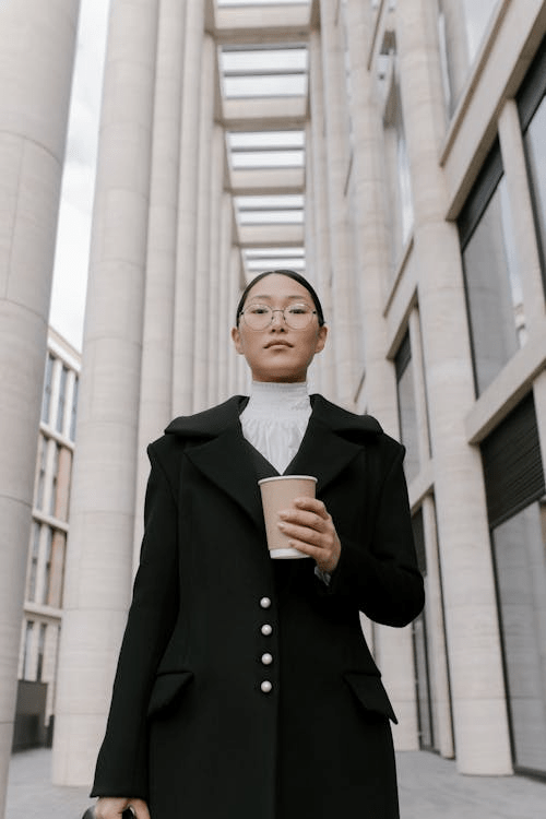 Young Asian woman in a suit stands in a large office lobby.